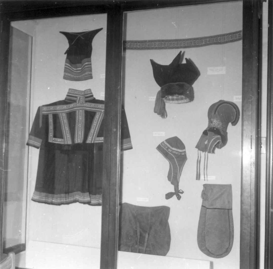 Utstillingsmonter med Kautokeino-drakt, Øst-Finnmark mannslue, hornlue, sekk og kaffepose fra samisk utstilling i California 1963.