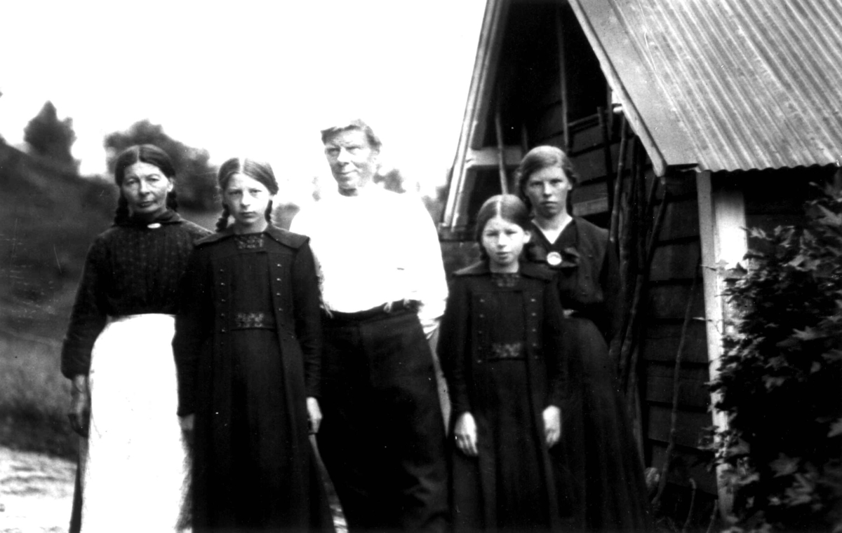Kvinne-, manns- og barnedrakt, gruppeportrett, Valle, Setesdal, Aust-Agder, antatt 1924. Gruppe stående foran hus. Fra "De Schreinerske samlinger" (skal oppgis).