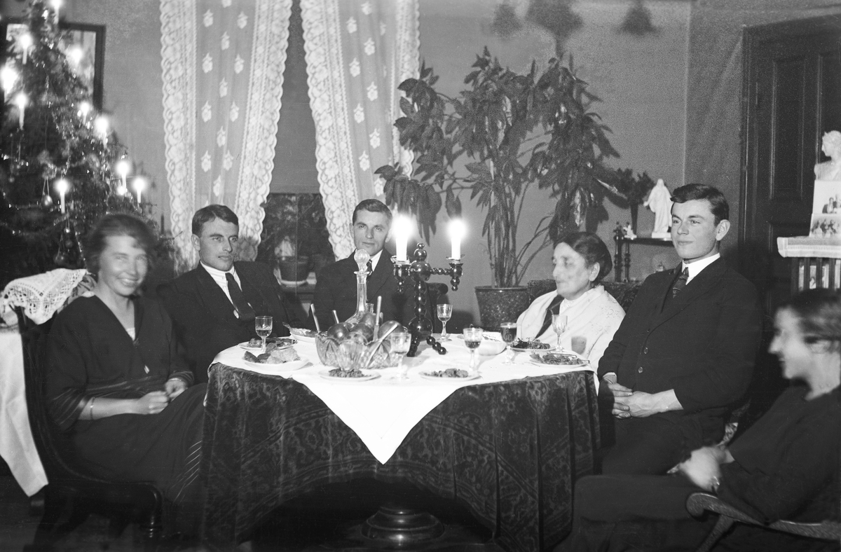 I stuen på Elverhøy rundt et bord sitter Guri, Thorleif og Dikka, Bjarne og Liv Arentz med pyntet juletre. Fotografert Julen 1923.