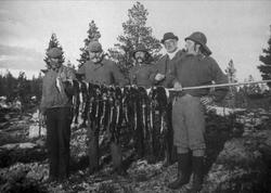 Avfotografering. Fem mannfolk på fisketur viser fram fangste