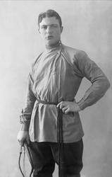 Portrett, mann med sigarett i munnen, pisk i hånda og todelt