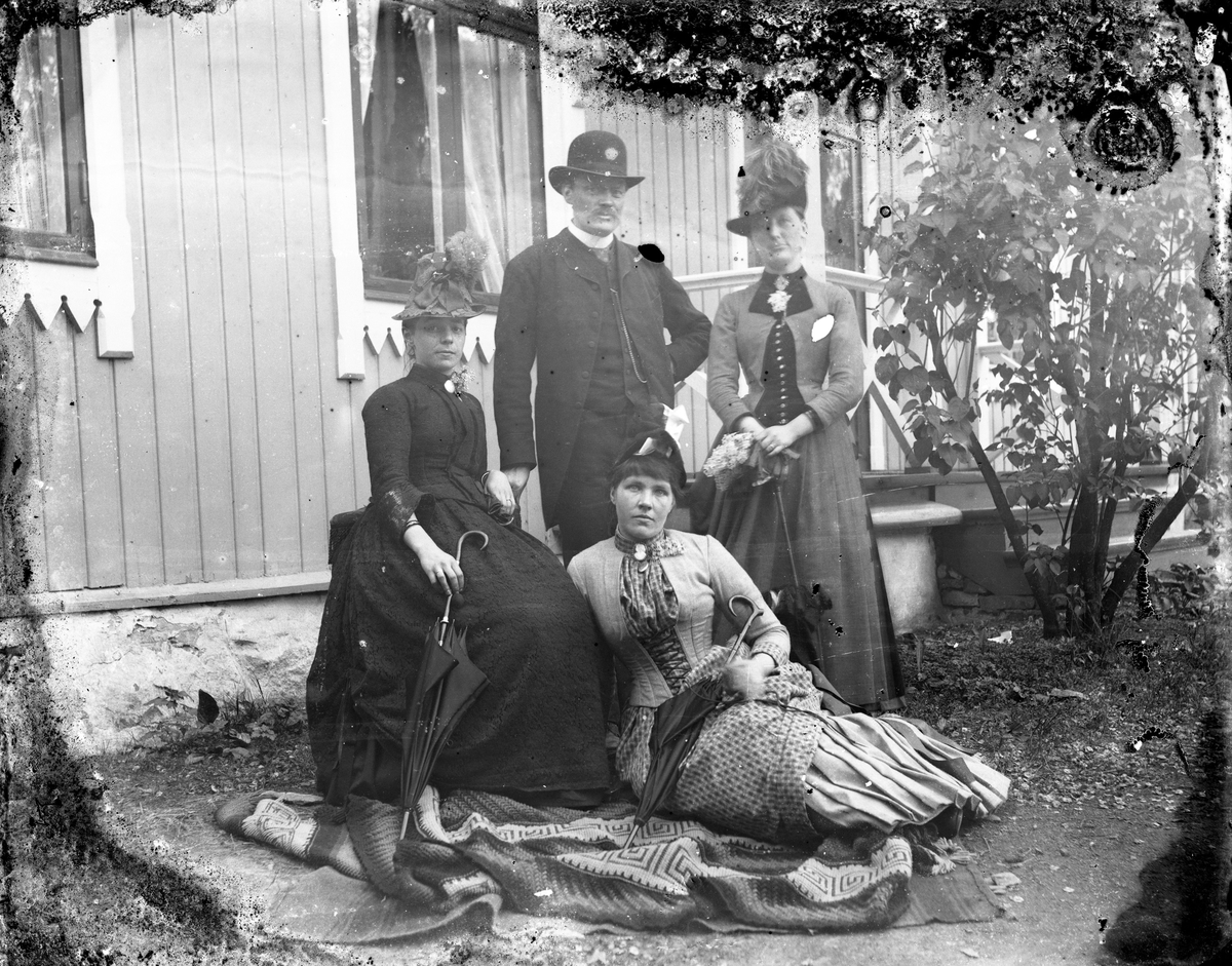 Gruppe, tre kvinner og en mann ute i hagen foran huset.