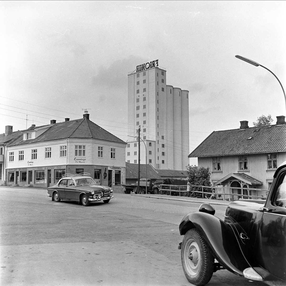 Mysen, Eidsberg. 26.08.1960. Bygninger, kornsilo og biler av typen Volvo Amazon med Citroën 1934-57 i forgrunnen.