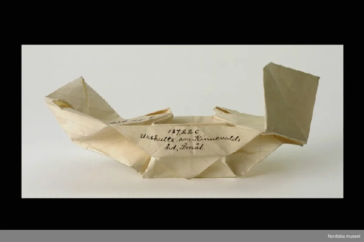 Inventering Sesam 1996-1999:
L 14 cm
Pappersvikning, vikt av linjerat papper, föreställande en vikingabåt. En samling pappersvikningar inv.nr. 187.226-232.
Helena Carlsson 1996