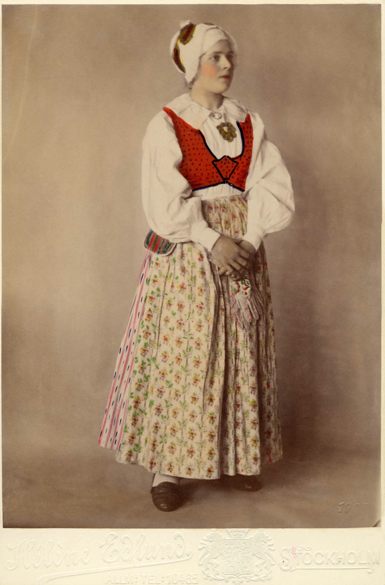 En kvinna poserar i en dräkt från Sunnerbo härad, Småland.