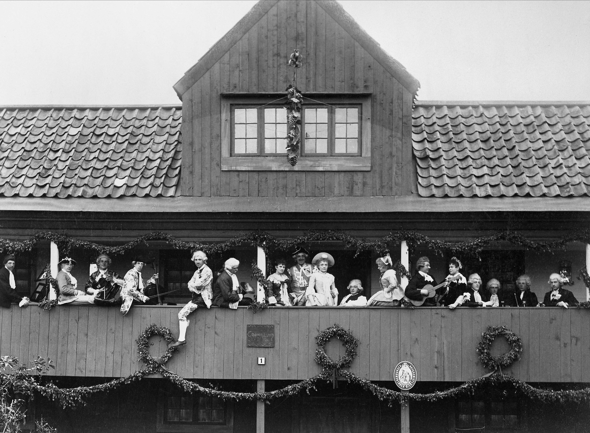 Skansens vårfest 1894. Ett sällskap män och kvinnor iförda 1700-talsdräkt på Gröna Lunds loft. Vissa av männen med instrument.