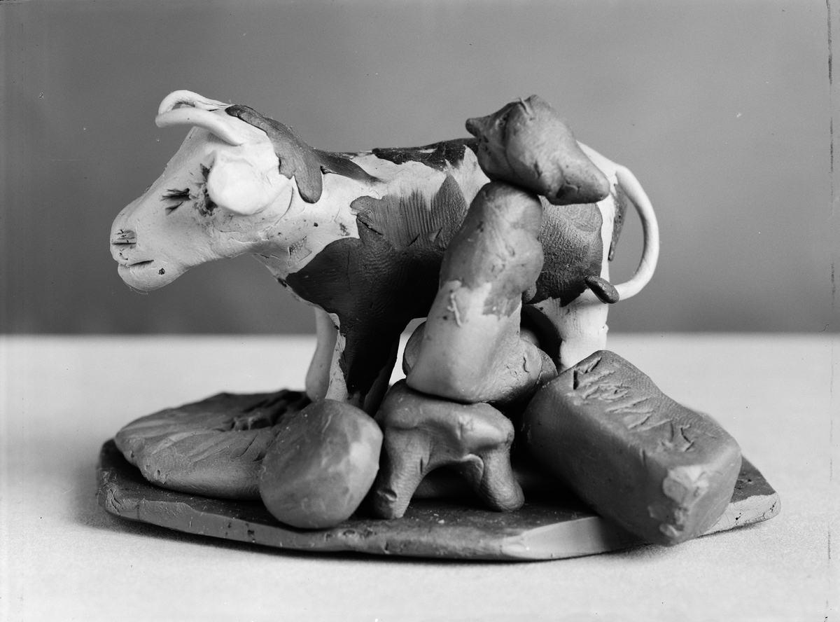 Figur av lera föreställande kvinna som mjölkar en ko