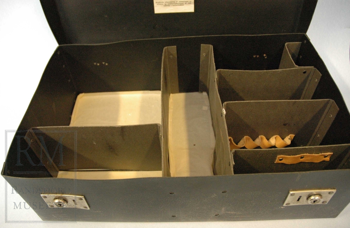 a) koffert i stiv papp. 2 stk lås i blankt metall med nøkkelhull.Kofferten inneholder 8 rom adskilt av pappvegger. 
b) pinsett
c) plaster
