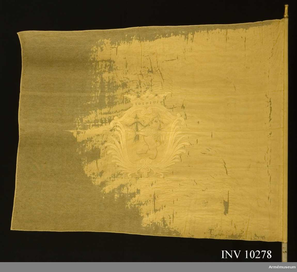 Den ursprungliga sidenfärgen, gul, är blekt gulbeige. Krönt sköld med ett stående lejon med  spänd båge och pil. Stången är avsågad.