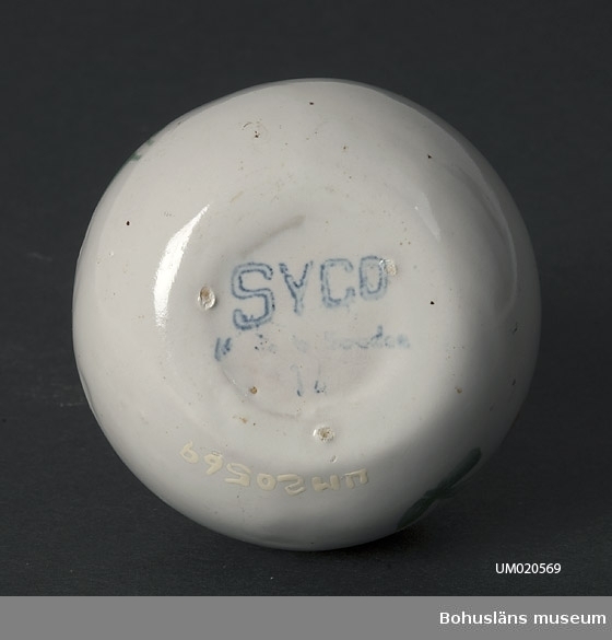 Närmast sfärisk nederdel och något konande hals. Vitglaserad med målad blomdekor och namnet: "Fridafors." 
Märkt i botten med stämplad, blå signatur: "SYCO Made in Sweden. Ib."
Troligen 1940-1950-talen.
