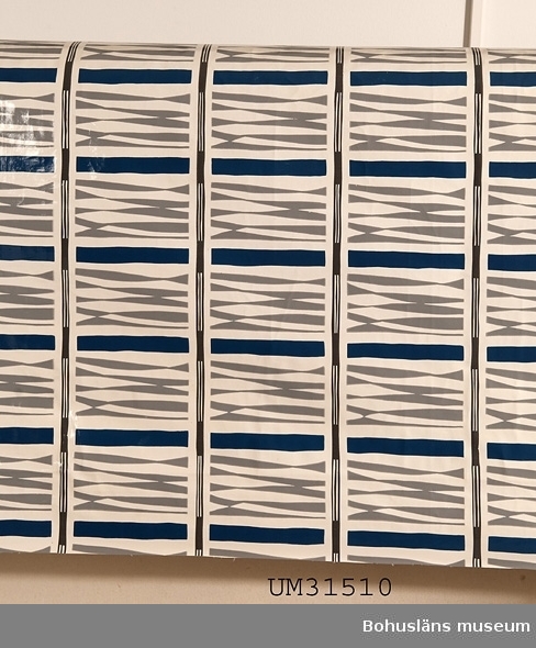 Rektangulär plastduk av PVC-skikt på bomullsväv från 1950-talet. Vit botten med tryckt abstrakt mönster i mellanblått och två grå nyanser.
På baksidan en liggande oval stämpel tryckt i vitt, inuti med texten:
VÄVPLASTDUK FRÅN
Anneberg
DUKSPECIALISTEN
Se Bilagepärmen UM31510 för reklamblad från företaget.

Duken har använts till matbordet i allrummet i en sommarstuga i Sundsandvik, Bohuslän. Duken var avpassad för bordet i utdraget skick. I allrummet finns panoramafönster mot fjorden, på motsatt vägg ett högt placerat långsmalt fönster,  en murad öppen spis, lackat trägolv med smala plank, vita väggar och tak. För interiörfoto, se UMFA55058.

Föremålet har använts av familjen Abrahamson i deras sommarstuga i Sundsandvik, byggd 1939.
För ytterligare upplysningar om förvärvet, se UM031385.