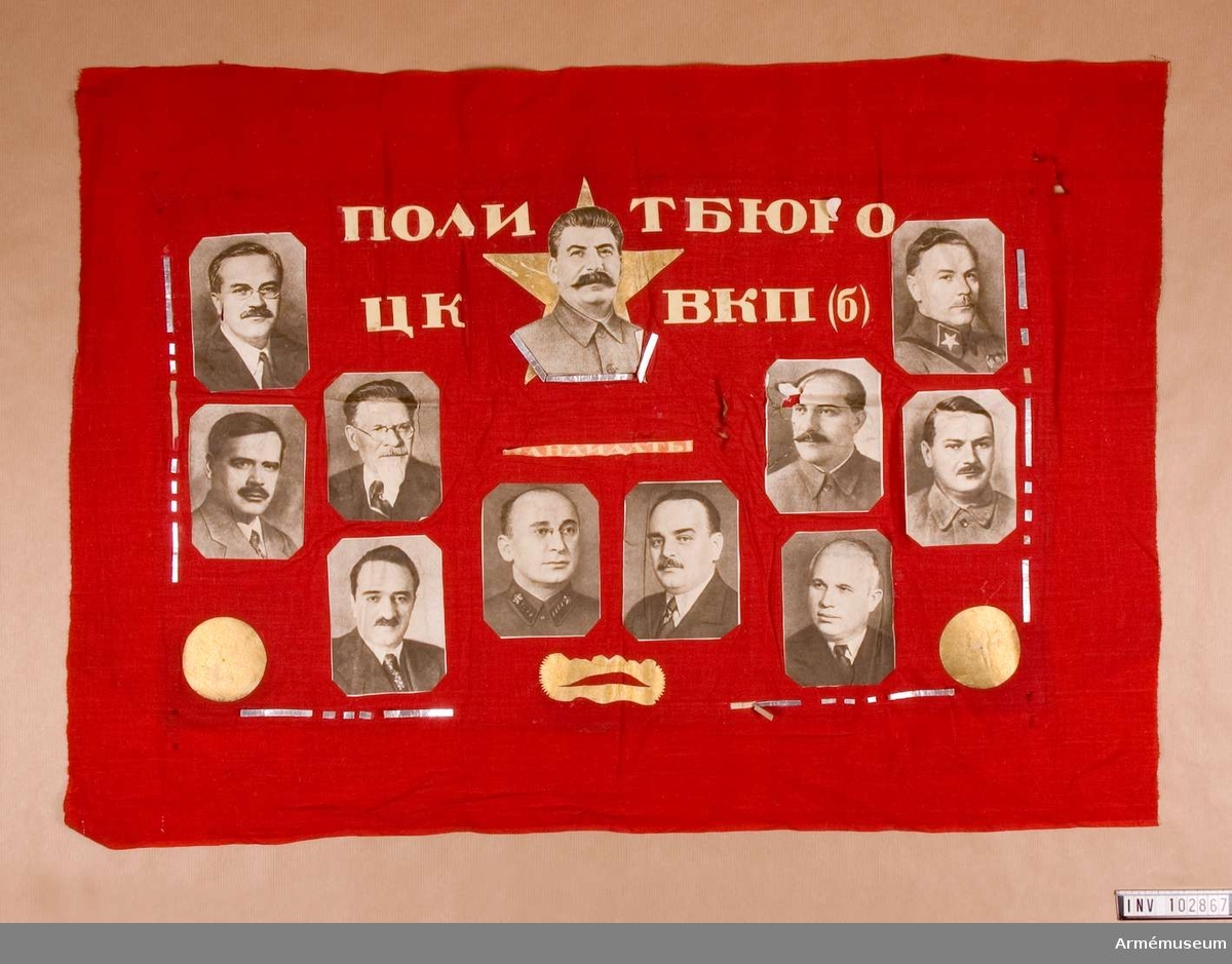 Grupp M V.
Röd flagga av bomull med uppklistrade 11 fotografier av politiker.