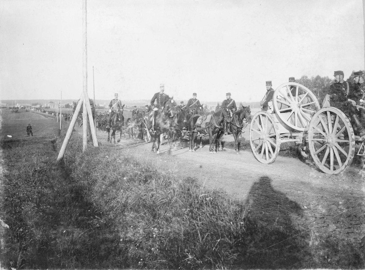 Kronprins Gustav (Gustav V) rider förbi en marschkolon med artillerister till häst, möjligen Vaxholms artillerikår A 8, under en manöver i Närke 1895.