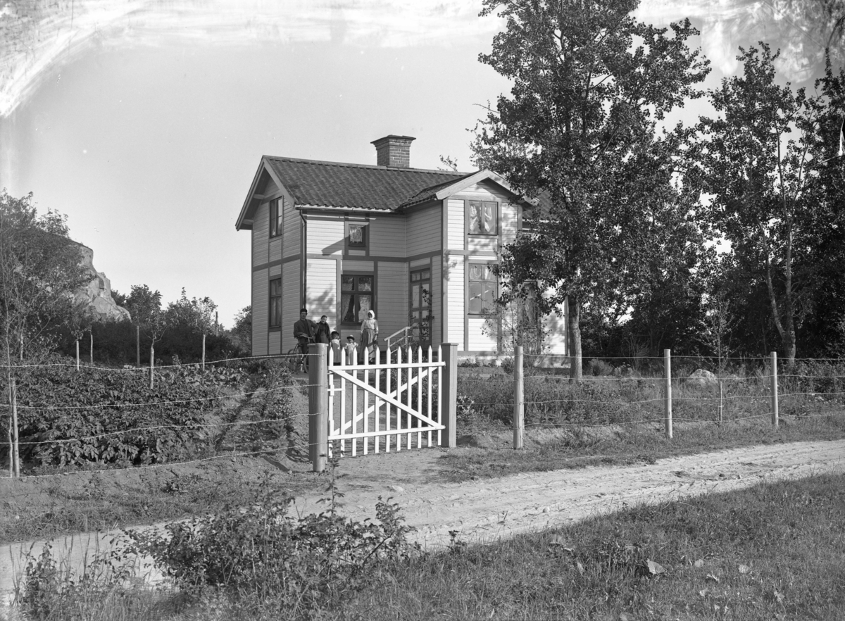 Grupp framför bostadshus, oidentifierad, troligen 28 juli 1904