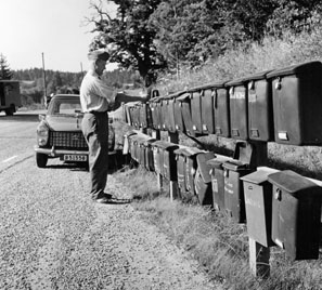 Bilåkande lantbrevbäraren Erik Johansson på linjen
Åkersberga-Singö-Björnhuvud-Åkersberga. Brevlådesamlingen vid Singö handel.

Foton augusti 1961.