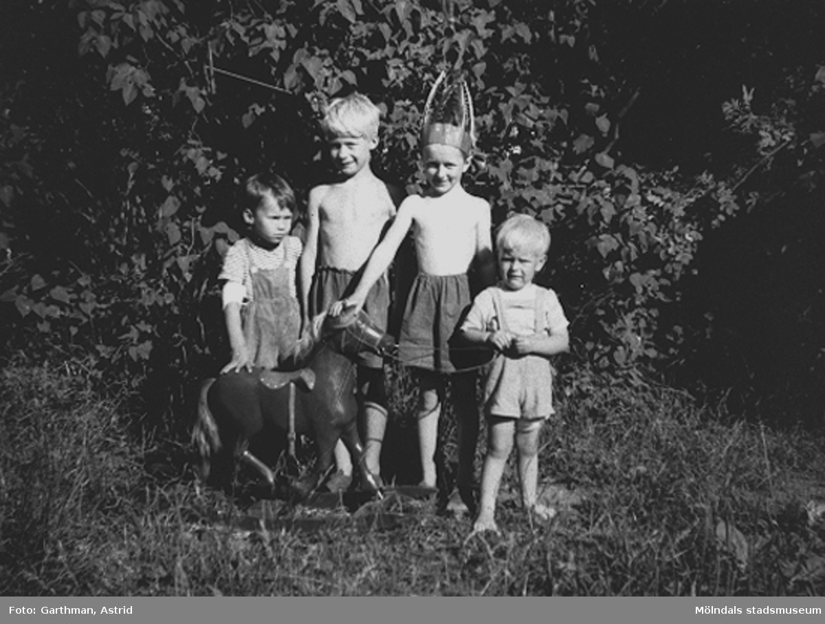 Fyra små pojkar leker cowboy och indianer i bersån på Barnhemsgatan, år 1952. Hästen är tillverkad av en snickare på API (Pumpindustrin i Krokslätt). Från vänster: Bosse och Örjan Stolth samt Leif och Alf Garthman.