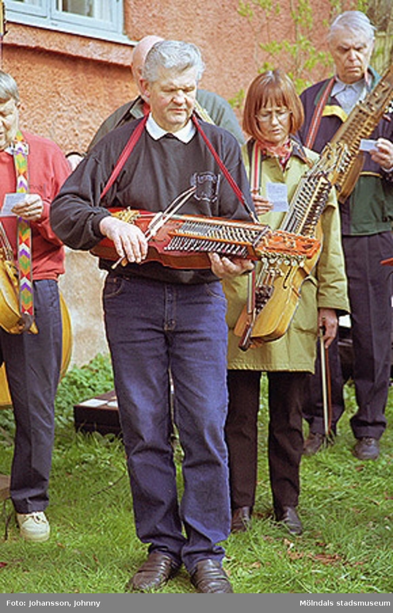 Kvarnbydagen 28 april 2002. Museitekniker Sven-Åke Svensson spelar nyckelharpa i Lommebôs spelmansslag då Stensjöns församling har friluftsgudstjänst i Kvarnbyparken.