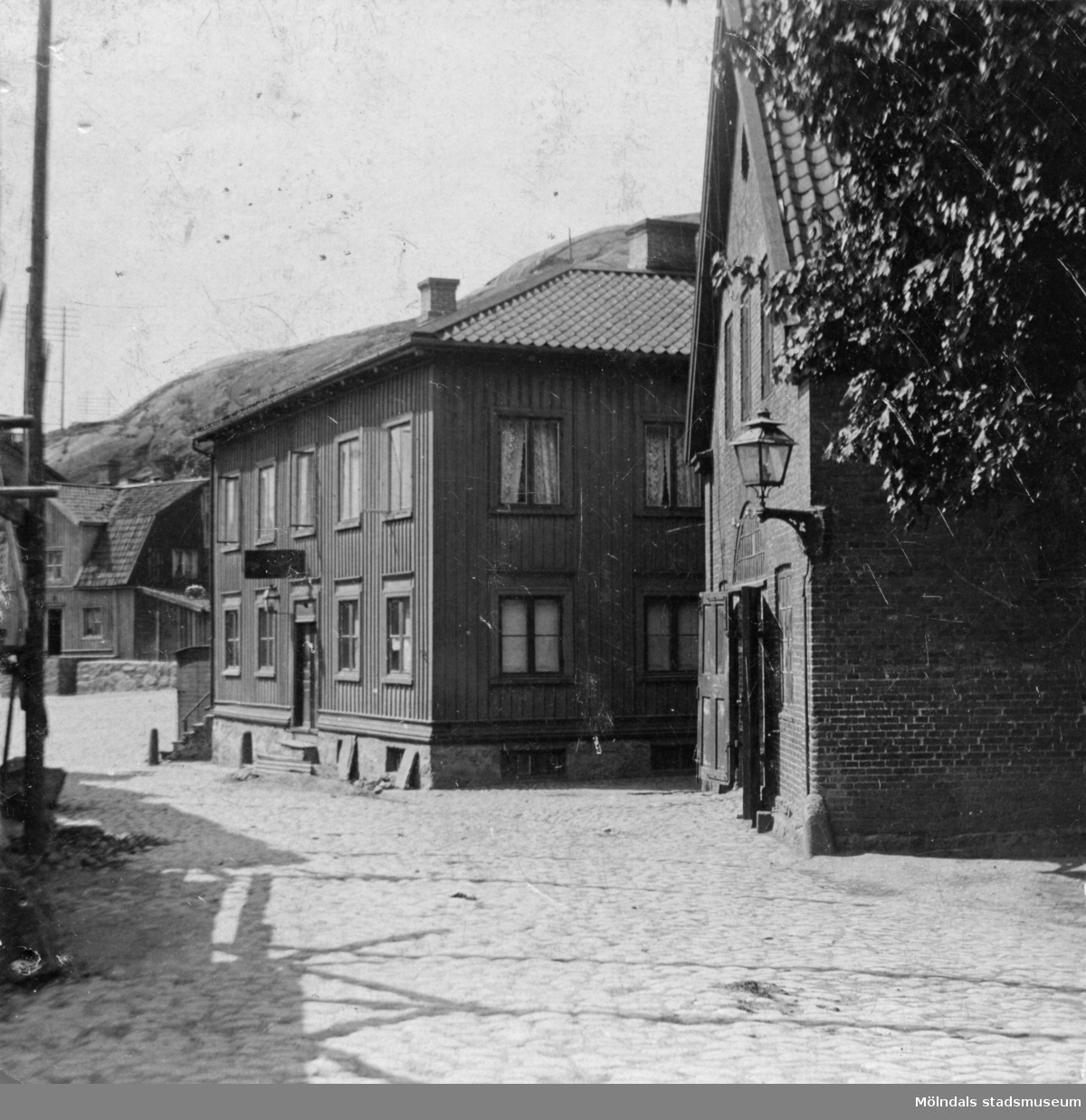 Malmgrens hus (Kvarnbygatan 45) och Delbancos stall längst ned i Kråkan vid Gamla torget, cirka 1900-tal. På baksidan av fotot står det skrivet: Mormors bröderna Åberg ägde fastigheten vid torget i Mölndal. Här föddes Hilding Kennedy. 7/7-1888.