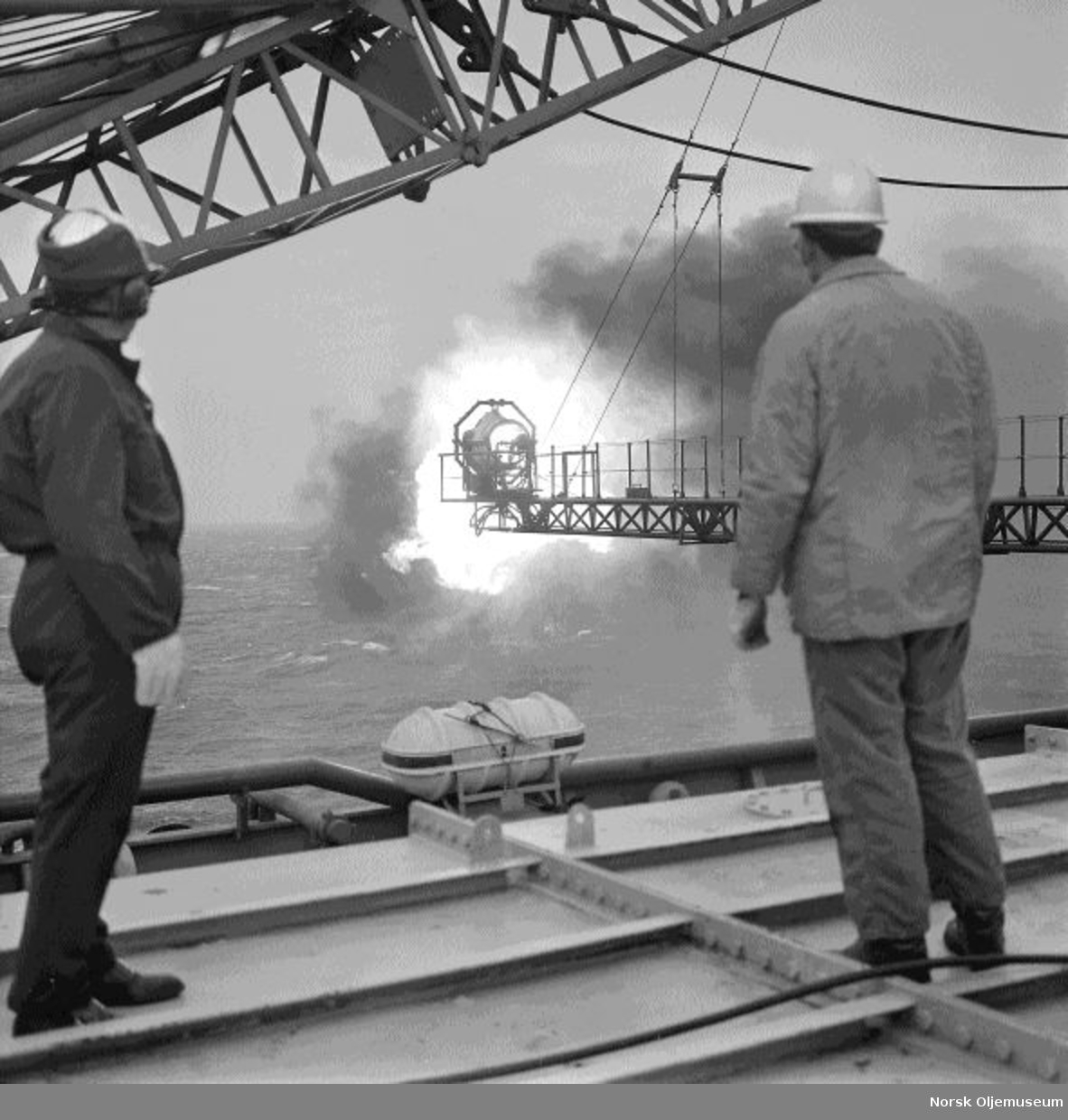 To menn studerer en flammebom på boreplattformen "Gulftide".