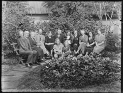 Gruppe - antakelig familie samlet i en hage i en bakgård, an