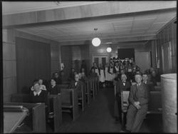 Ukjent gruppe mennesker i forsamlingslokale, serveringsperso