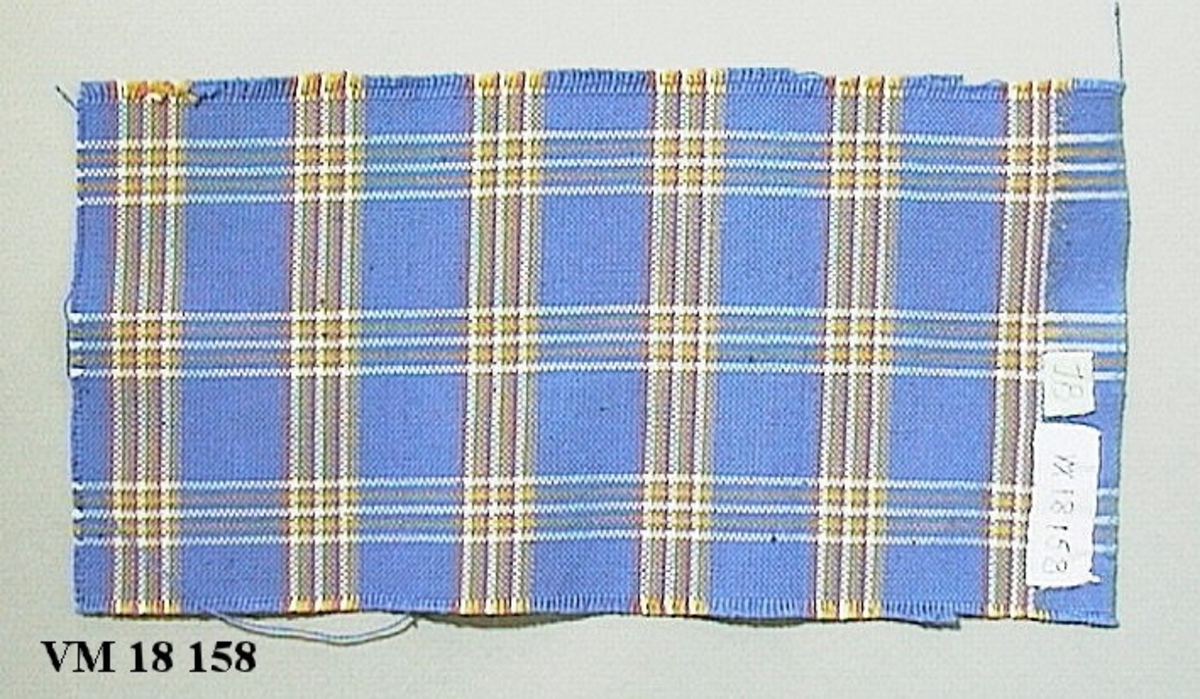 Handvävt. Bomullstyget Tösse i en annan färgställning. Den blå färgen är annorlunda än den i det av AB Gustav Werner uppvävda tyget. VM 18 150.

Motiv/dekor: Rutigt.