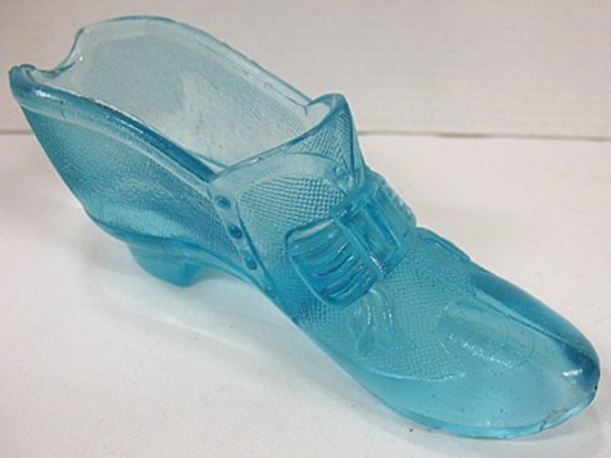 Ett par prydnadsskor av pressat glas.

Enligt givarna kallade ''Lyckans skor''. Skorna har inpressat i glaset en rosett ovantill samt knäppning i sidan. Skorna stod i givarnas barndomshem.

Ursprungligen användes sådana här skor som cigarrställ.