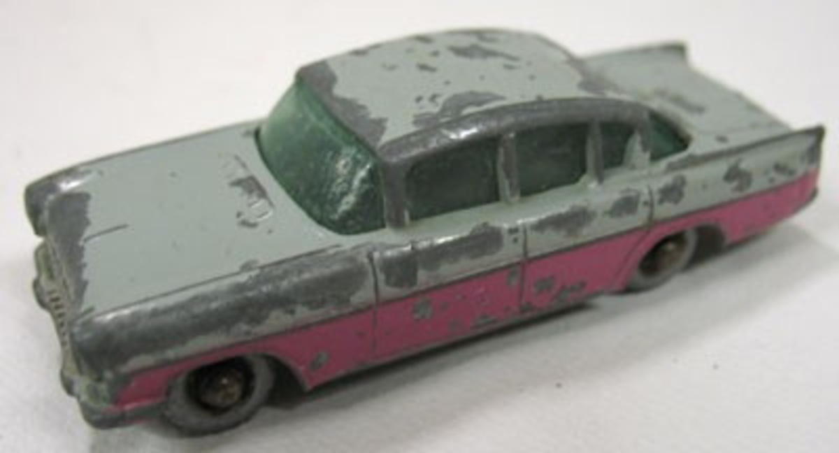 Grå bil med rosa sidor.

En av 12 st. leksaksbilar av metall tillverkade av Lesney Products & Co. Storbritannien.

Förutom personbilar finns en tankbil, en dubbeldäckad buss, en kranbil samt en lastbil. Bilarna är tillverkade under 1960-70 talet och är samtliga av metall. Flera av bilarna är hårt slitna.
Längd 5,2-8,2 cm.