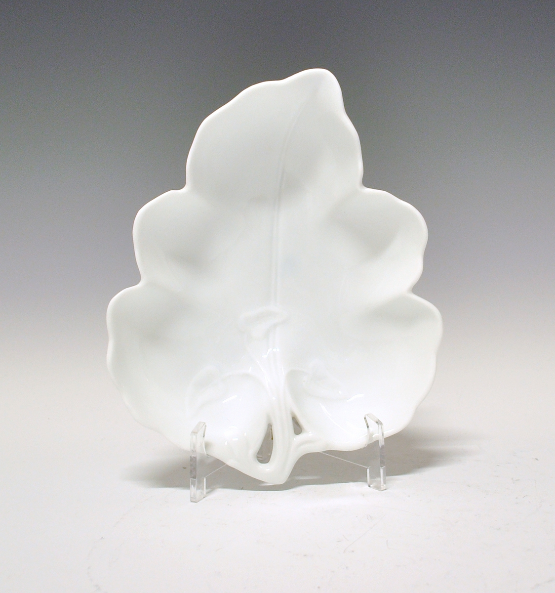 Skål av porselen. Formet som et eføyblad, gjennombrutt ved stilkfeste, med lavt bladrelieff ut fra dette. Hvit glasur, uten dekor. Hjerteformet fot.
Modell 43.2