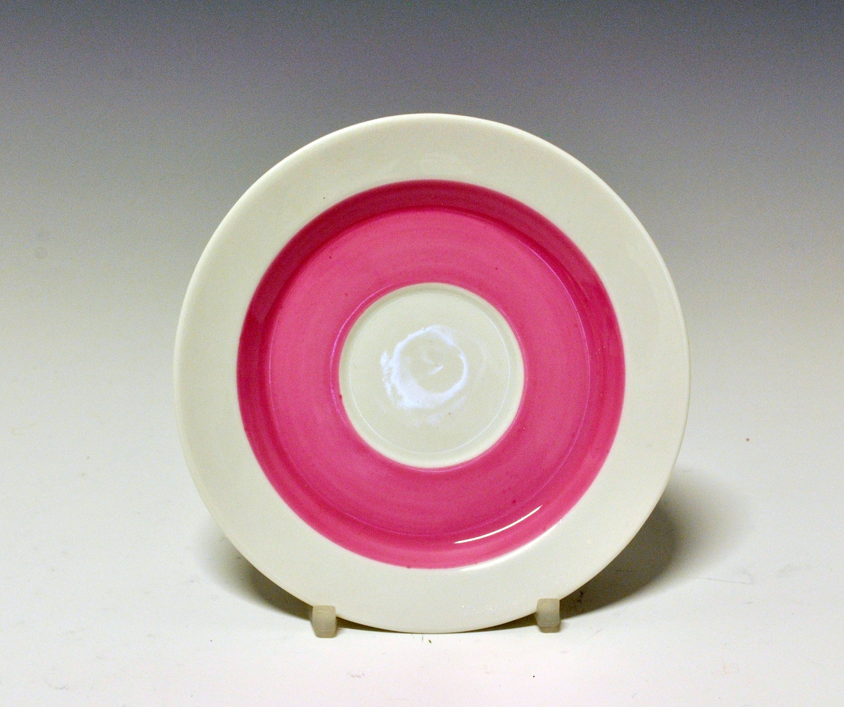 Kaffeskål av porselen, dekorert med et rosa bånd innerst på fanen.
Modell: Style