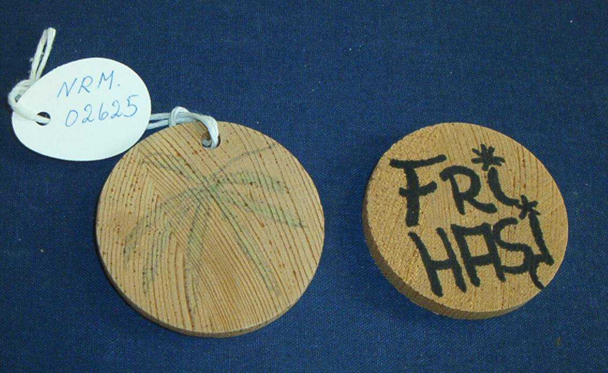 To runde tremerker med hjemmelaget preg. På den ene står det "FRI HASJ". Den andre har et påtegnet cannabisblad.