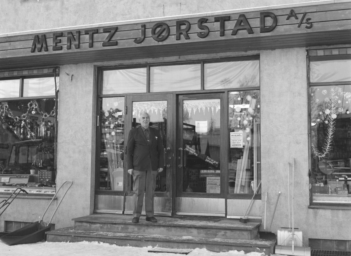Mentz Jørstad AS, Jern og byggevareforretning i Nygata, Brumunddal. 
Juleutstilling, juletre. Bernhard Bakken utenfor forretningen.