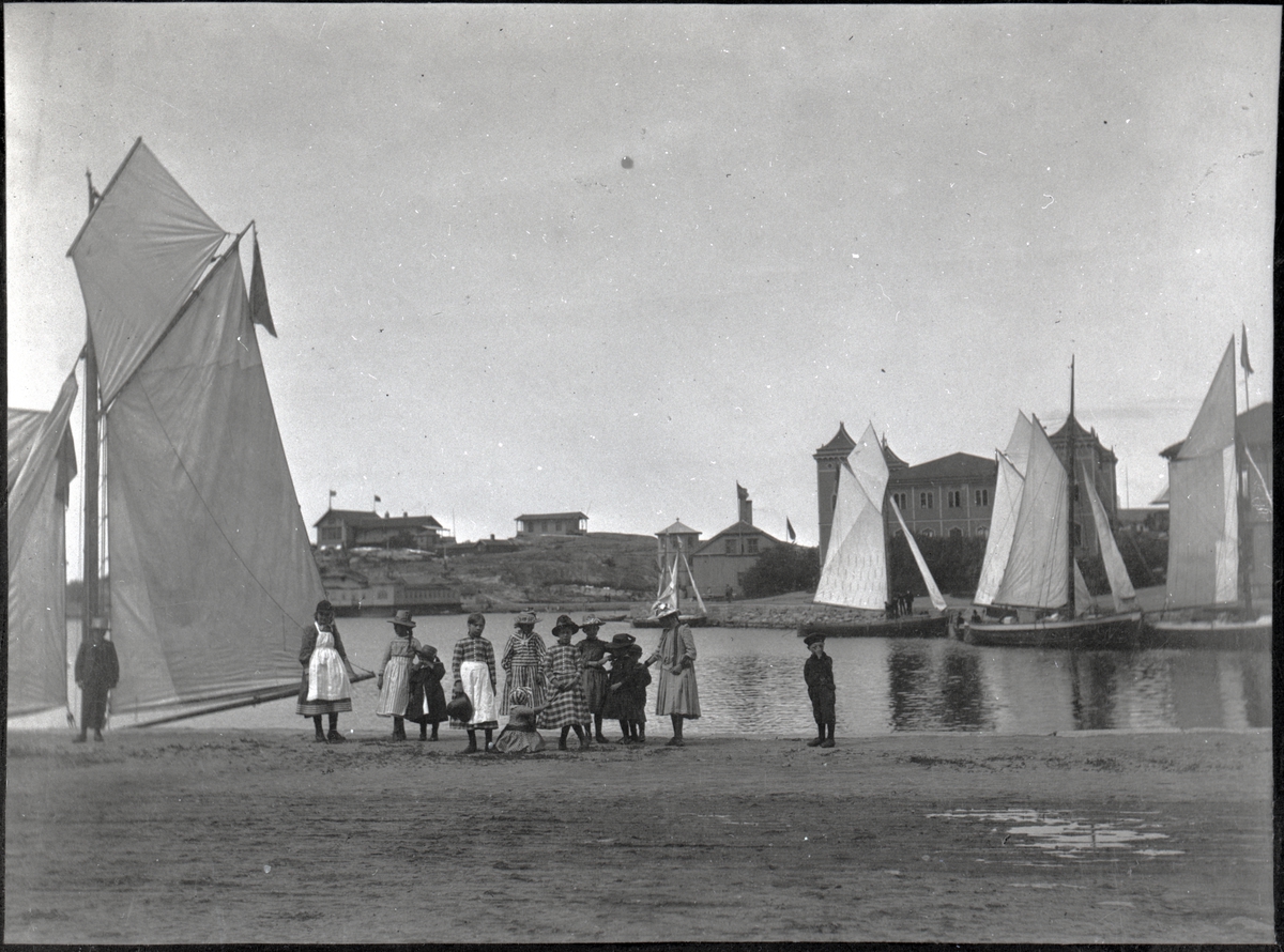 Segelbåtar i Strömstads hamn. På kajen står barn uppställda.