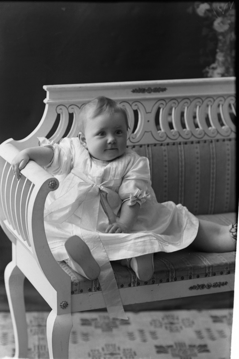 Studioportrett av et lite barn på en benk.