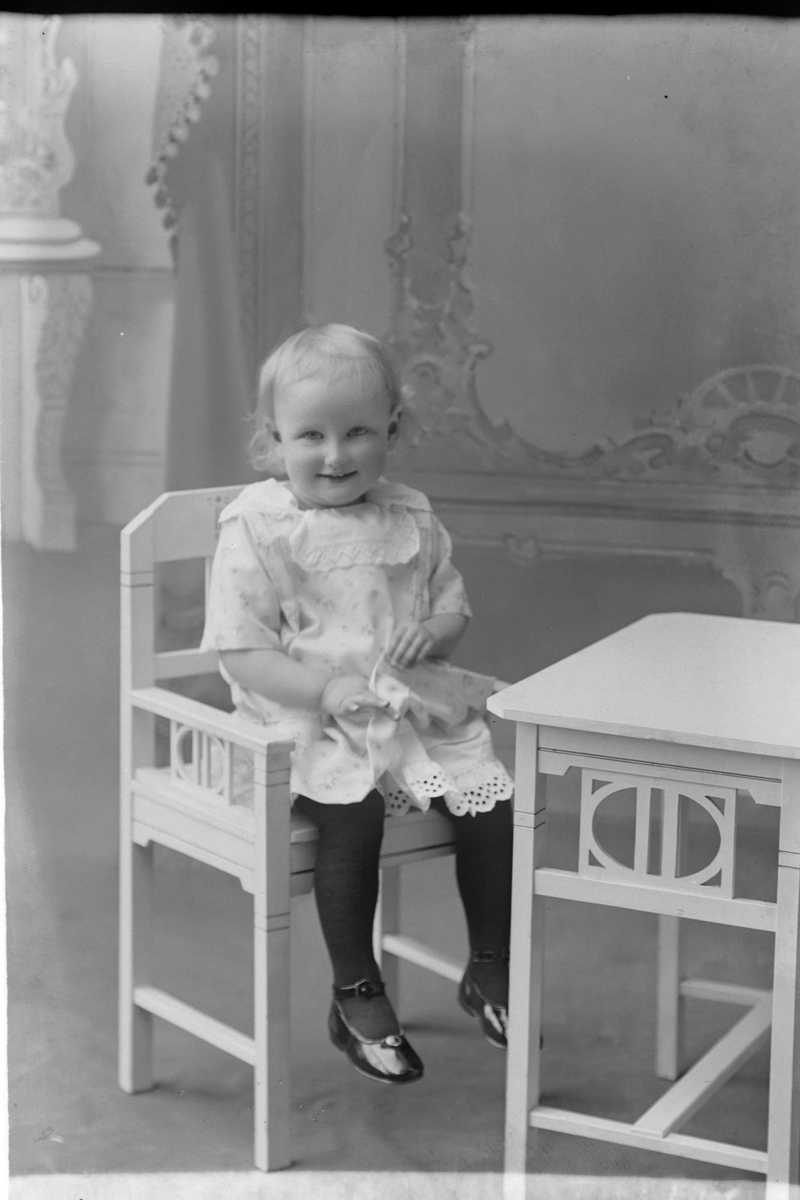 Studioportrett av et lite barn som sitter i en stol.