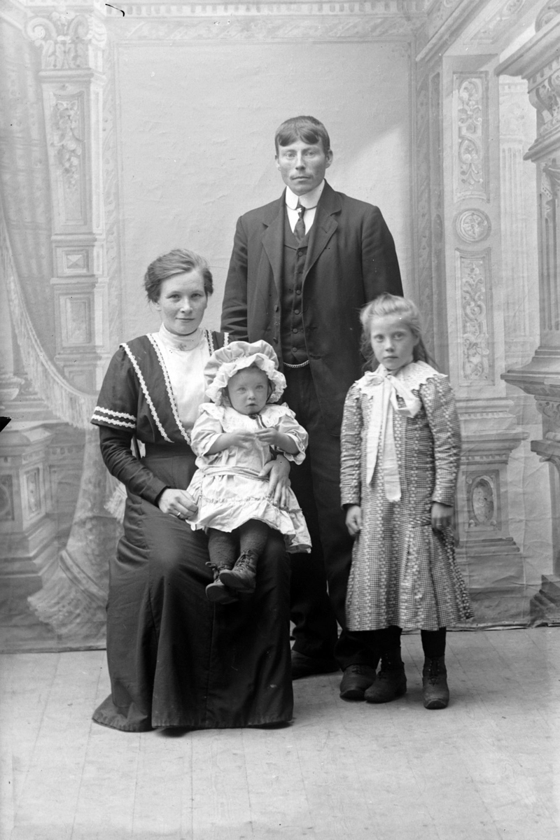 Studioportrett i helfigur av Knut og Emma Andersen med familie.