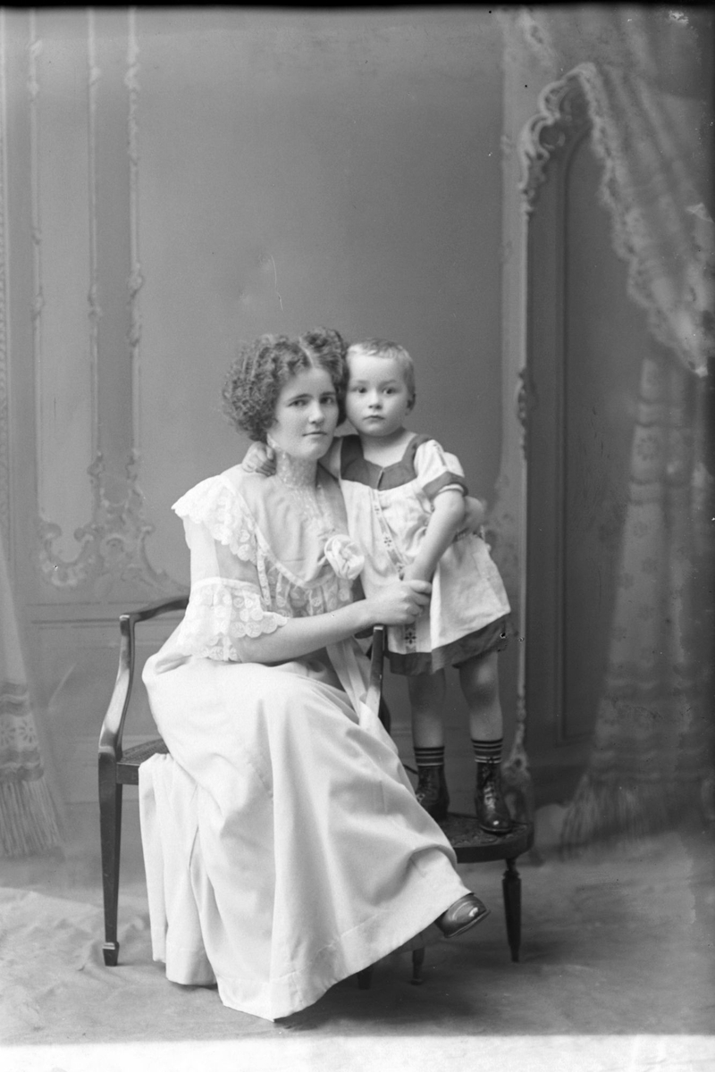 Studioportrett av en kvinne med et lite barn ved siden av seg.