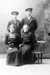 Studioportrett av en gruppe på fire i helfigur.