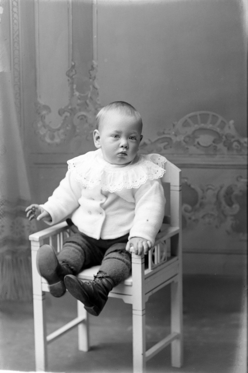 Studioportrett av et lite barn på en stol.