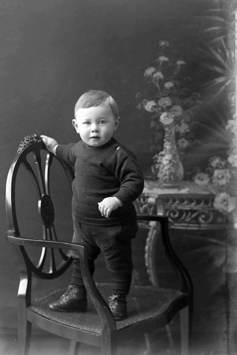 Studioportrett av en liten gutt på en stol.