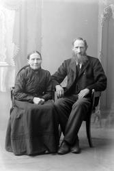 Studioportrett av to eldre personer som sitter.