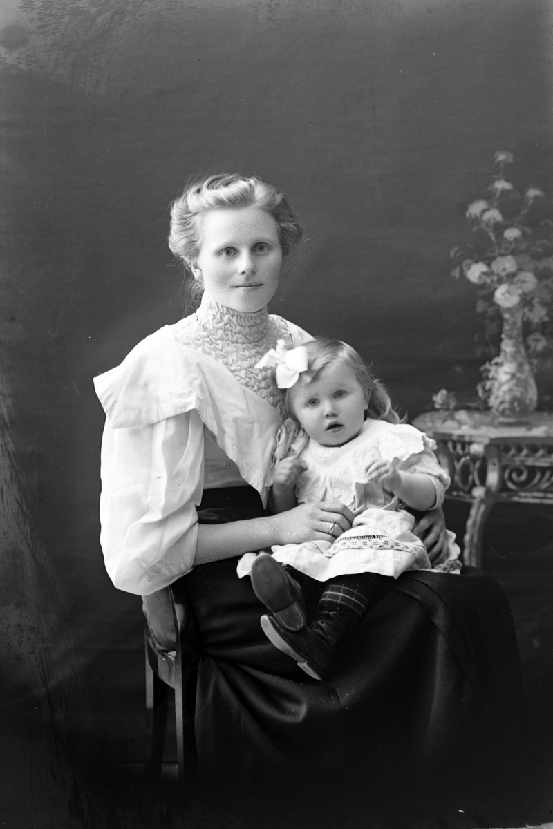 Studioportrett av en kvinne med et barn på fanget.