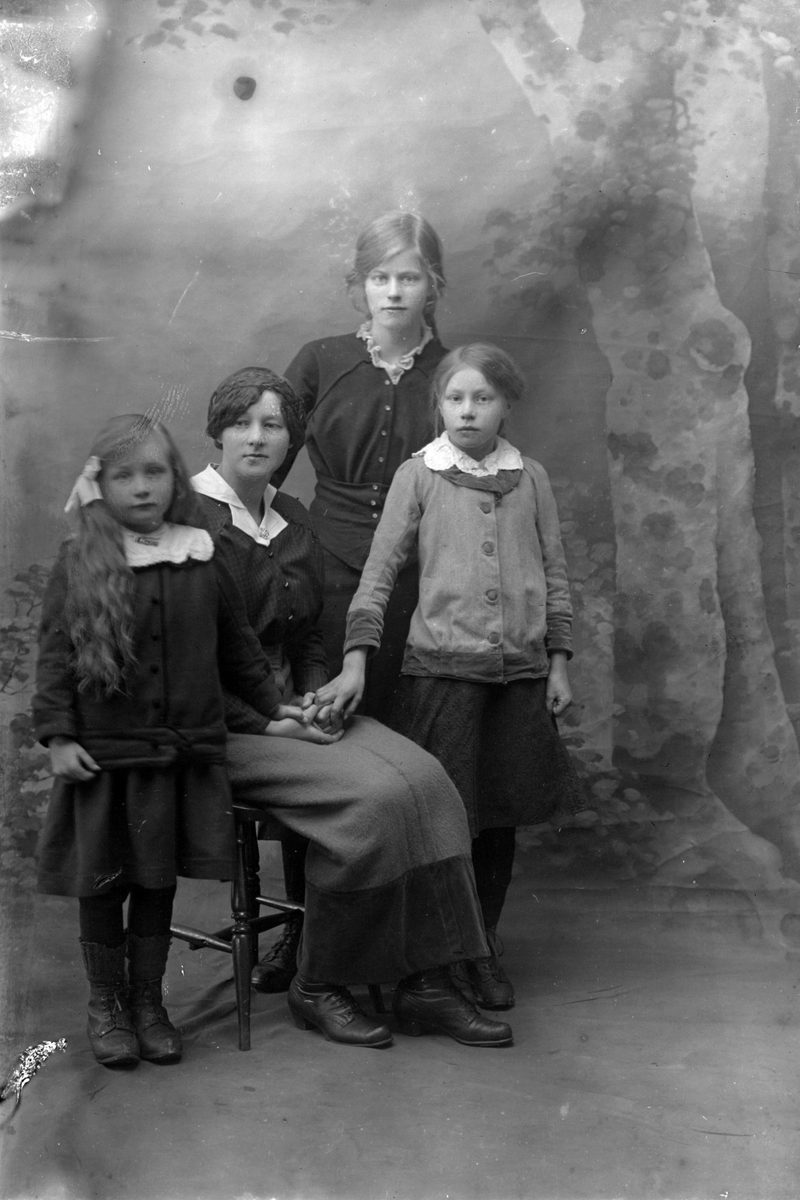 Studioportrett av en kvinne omgitt av tre barn.