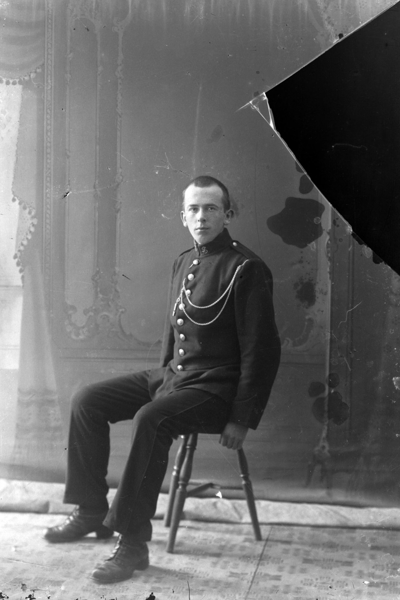 Studioportrett av en mann i uniform som sitter.
