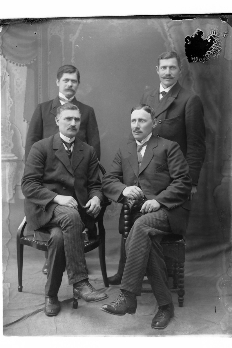 Studioportrett av fire menn i helfigur.