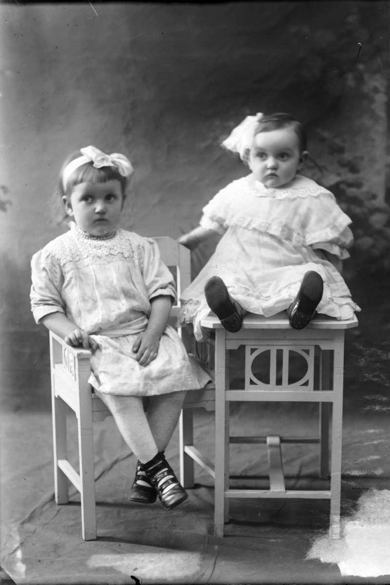 Studioportrett av to små barn som sitter.