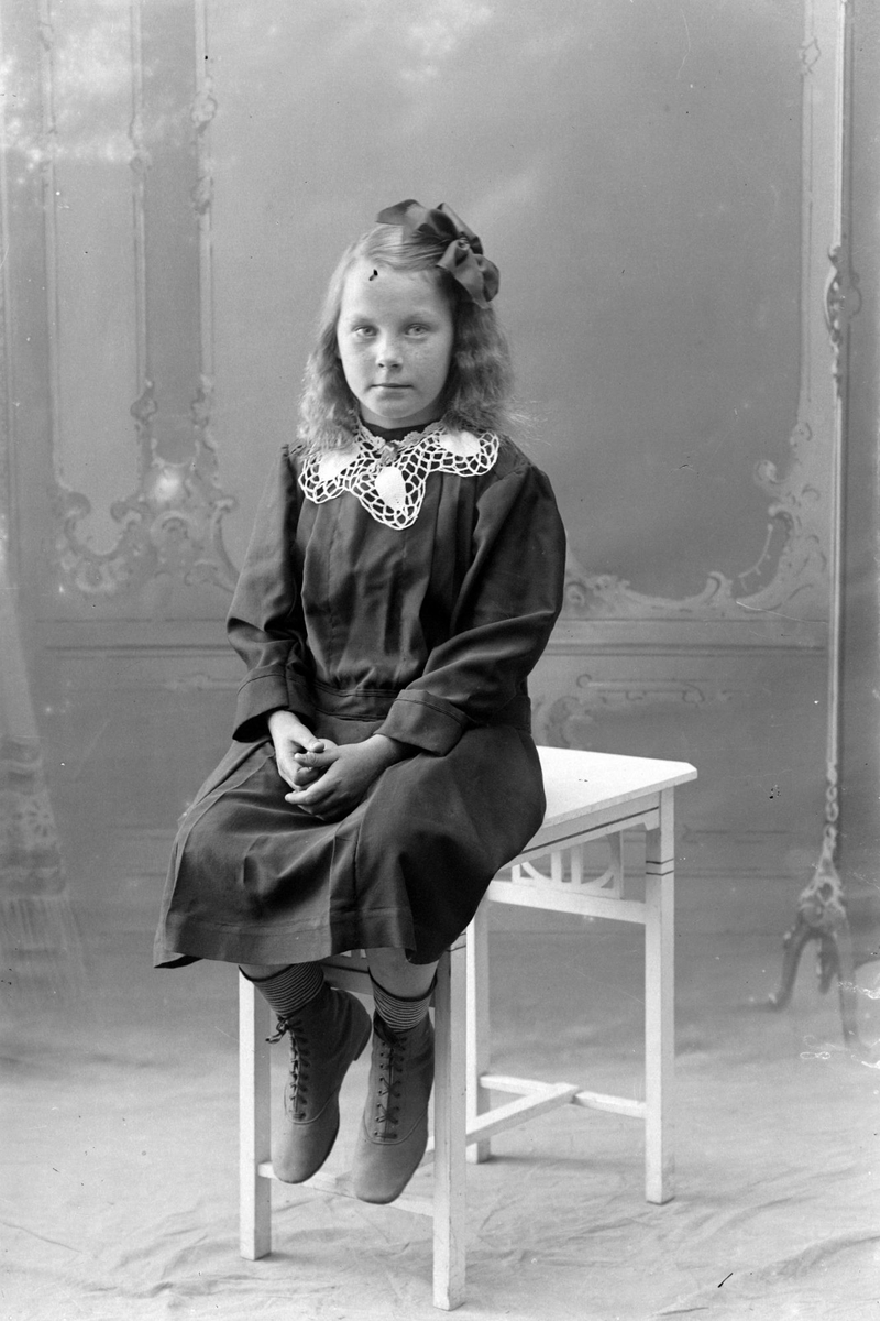 Studioportrett av en ung pike som sitter på et bord.