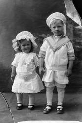 Studioportrett av to barn som holder hender.