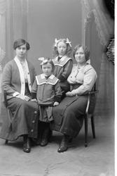 Studioportrett av to kvinner med to barn.