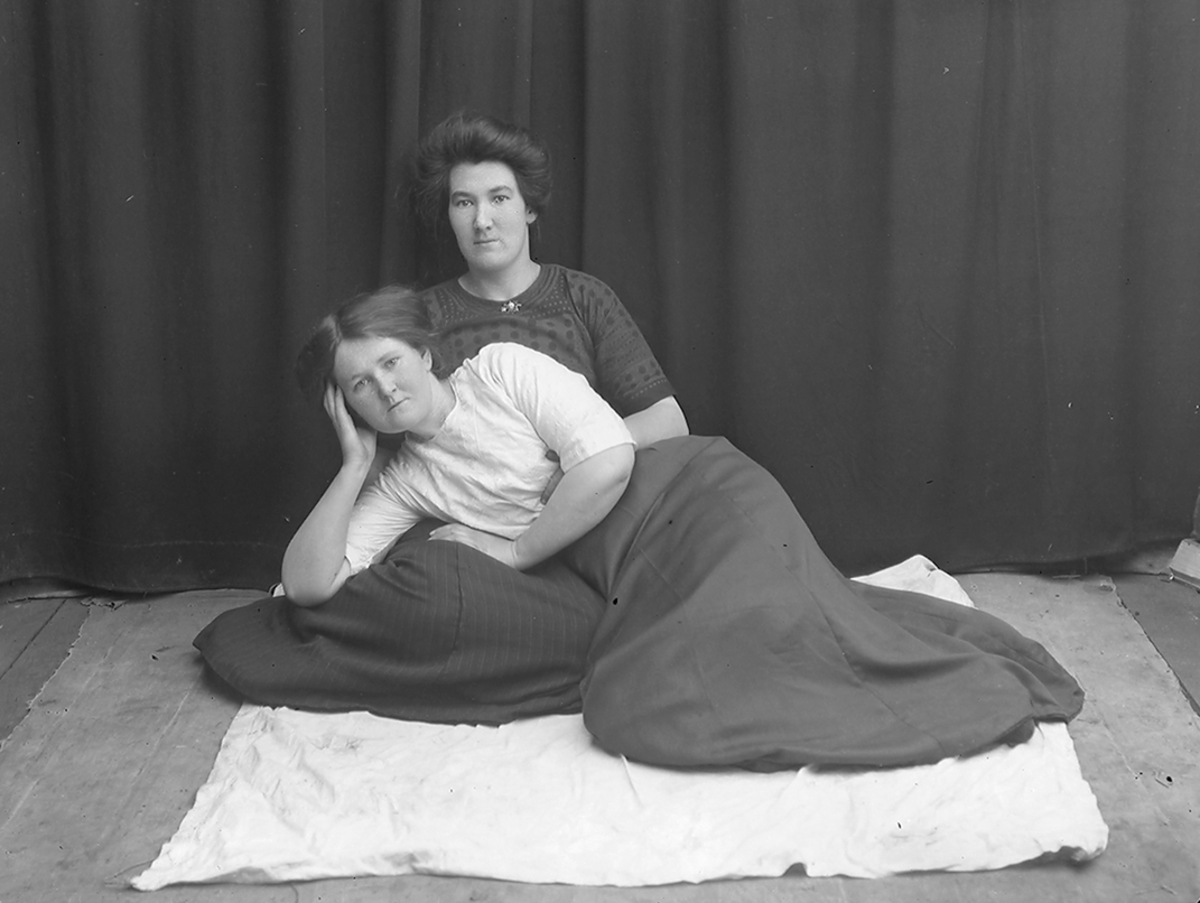 Portrett. 2 kvinner i 20-30-åra. Sitter/ligger på gulvet. Bildet er tatt på Reine i Lofoten.